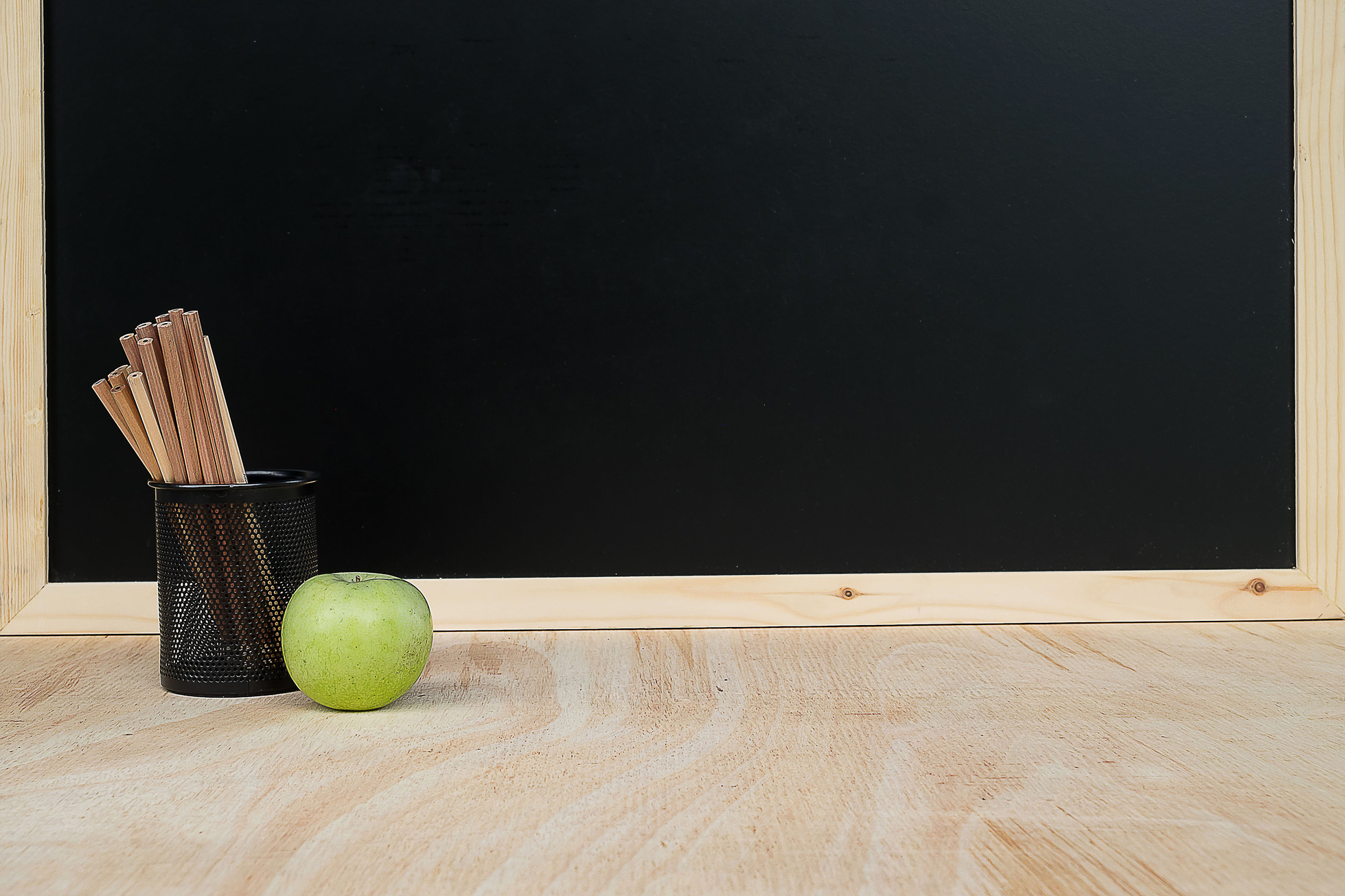 Teacher's desk with a pencil, apple and other equipment.